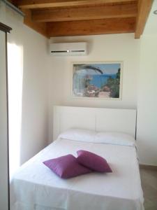 圣泰雷萨迪里瓦Pozzo Lazzaro Apartments的白色的床和紫色枕头