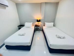 曼谷Bed by Tha-Pra SHA Plus的小型客房配有两张床铺、桌子和台灯。