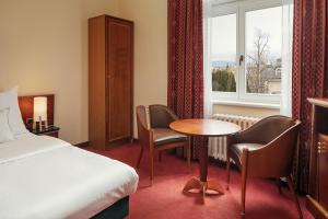 卡罗维发利Spa Hotel Villa Smetana的酒店客房带一张床、一张桌子和椅子