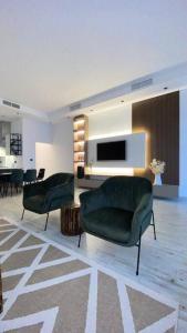阿尔科兰Chalet 2200的客厅配有两把绿色椅子和电视