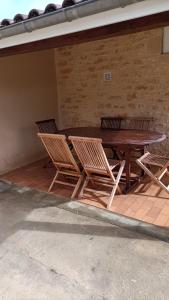 萨尔拉拉卡内达Maison T4 a 6 minutes à pieds de Sarlat的砖墙旁的一张木桌和椅子