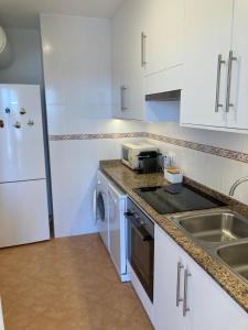卡拉恩弗卡特SUNSET MENORCA的厨房配有白色橱柜、水槽和炉灶。