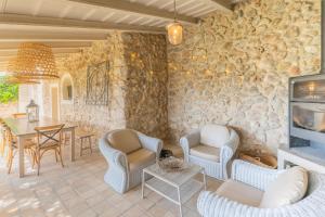 凯玛丽Pintor - Rustic Mallorquin town house 3 bedrooms and pool in Caimari的客厅配有椅子、桌子和石墙