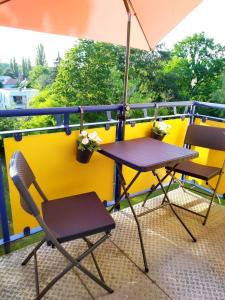 德累斯顿Helles Apartment mit Balkon am Großen Garten nahe Stadtzentrum的阳台配有两把椅子和一张桌子,阳台配有遮阳伞