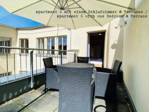 波茨坦Amaroo - Apartments Potsdam “Brandenburger Tor”的阳台配有桌椅和遮阳伞