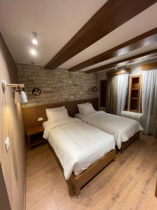 吉诺卡斯特Palorto Hotel的卧室设有2张床,设有砖墙