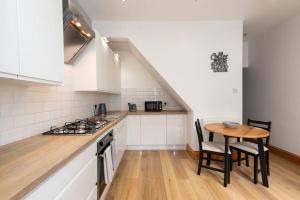 达灵顿Trafalgar Terrace的厨房配有白色橱柜和木桌