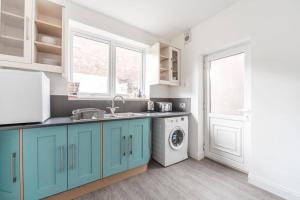 赫尔Cosy home near Port of Hull的厨房配有蓝色橱柜和洗衣机。