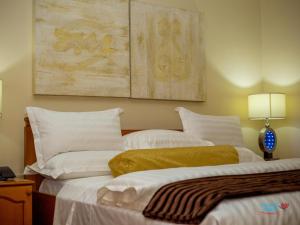 阿克拉Orchid Hotel的两张带白色枕头的床和墙上的绘画