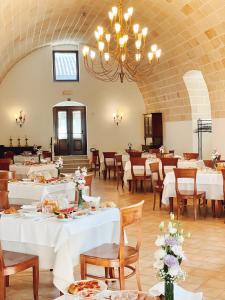 马泰拉西班牙塔农家乐的一间配备有白色桌椅和吊灯的餐厅