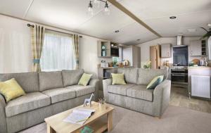 佩恩顿Hoburne Devon Bay stunning 3 bed luxury lodge的一间带两张沙发的客厅和一间厨房