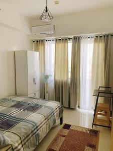 马尼拉SM Southmall condo 2br unit with mall view的一间卧室配有一张床和一个带风扇的窗户。