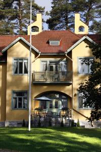 蓬卡哈尤Villa Urhola, Kruunupuisto的带阳台和草坪的大型黄色房屋