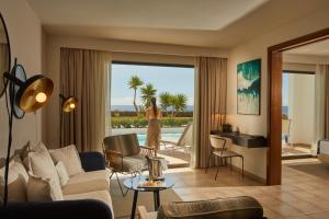 卡列罗港Secrets Lanzarote Resort & Spa - Adults Only (+18)的一间客厅,客厅里有一个女人从窗口望出去