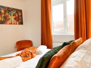 安德沃Antley House的一间卧室配有带橙色窗帘的床和窗户