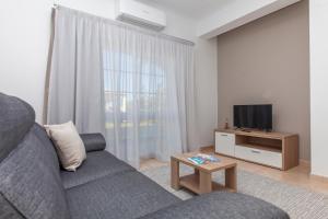 拉戈斯Atalaia Sol Aparthotel - tennis & heated pool in winter的客厅配有灰色的沙发和电视
