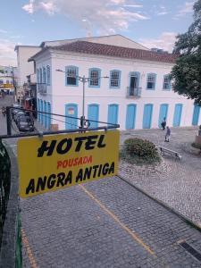 安格拉杜斯雷斯Hotel Pousada AngraAntiga的白色建筑前的酒店标志