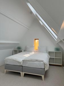 诺德韦克Aventure的一间位于阁楼的白色卧室,配有床铺