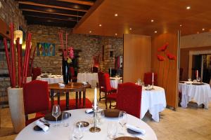多勒Hotel La Chaumiere的一间设有白色桌子和红色椅子及桌子的餐厅