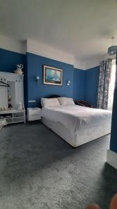 洛斯托夫特The Coventry Guest House的一间卧室配有一张带蓝色墙壁的大床