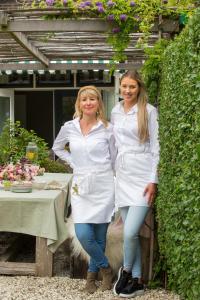 吕伐登De Roos Leeuwarden的两个穿着白色衣服的女人站在桌子旁边