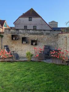 迪克斯梅德Vakantiehuisje aan de Ijzer的一座砖砌建筑,在院子里摆放着椅子和红色的鲜花