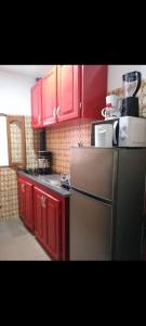 Angelus Meublés的厨房配有红色橱柜和不锈钢冰箱