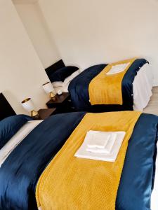 利物浦Family Home的两张带黄色和蓝色床单的床和上面的白色板