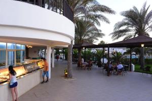 特里法Hotel Meninx Djerba的一家餐厅,人们坐在露台上的桌子上