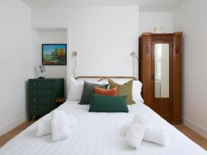 托基Saltwater Cottage的一张白色的床,上面有绿色和橙色的枕头