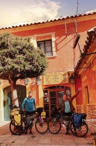 波托西Casa de Huéspedes María Victoria的两个人站在一座建筑物前面,骑着自行车