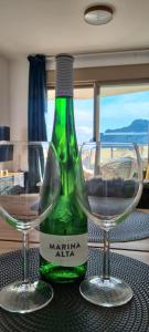 卡尔佩Esmeralda Suites Sunrise的一张绿葡萄酒和两张桌子上的玻璃杯
