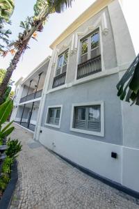 里约热内卢Hotel Castelinho的白色的建筑,有窗户和棕榈树