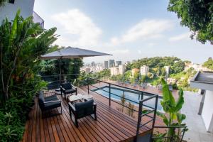 里约热内卢Hotel Castelinho的阳台上的木制甲板上配有椅子和遮阳伞