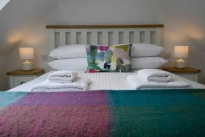 威廉堡The Barn的床上有五颜六色的毯子和毛巾
