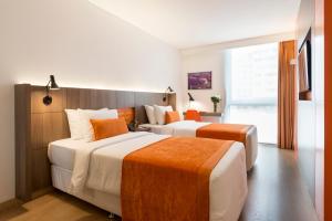 利马Libre Hotel, BW Signature Collection by Best Western的橙色和白色的酒店客房内的两张床