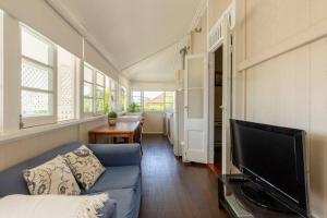 布里斯班Quaint & Cosy 1 Bedroom Apartment in Queenslander.的客厅配有蓝色的沙发和平面电视。