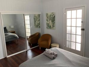 布里斯班Charming 1920's 4Br freestanding Plantation Qldr.的一间卧室配有一张床、一把椅子和镜子