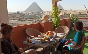 GizaGrand Pyramids In的两个女人坐在桌子上,拿着食物和金字塔