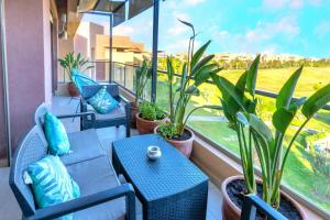 马拉喀什Cozy Golf Apartment Wifi 4k-TV Netflix的阳台配有桌椅和盆栽植物