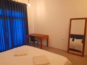 阿鲁甘湾Surf Gangs Arugambay的一间卧室配有一张床、一张书桌和一面镜子
