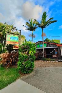 赫维湾Woolshed Eco Lodge的前面有标志和棕榈树的建筑