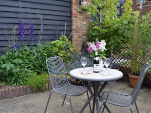 MatfieldDairy Cottage的桌子和两把椅子,配以酒杯和鲜花