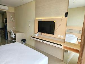 名古屋Nagoya thamrin apartment (Favehotel Building)的配有一张床和一台平面电视的酒店客房