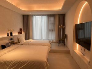 西安忆宿石玖设计师酒店(西安钟鼓楼回民街店)的酒店客房设有两张床和一台平面电视。