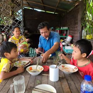 暹粒Phonluer Angkor Homestay,的一群坐在桌子旁吃食物的人