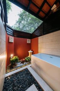 新加坡Kranji Sanctuary Resort的配有红色墙壁的客房内的浴缸
