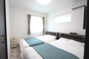 札幌TEINE WHITE HOUSE的一间卧室设有两张床和窗户。