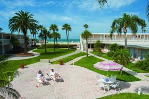 萨拉索塔丽都湾泳滩沙堡度假酒店的两人坐在海滩附近的庭院的椅子上