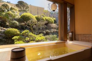 天川村Kadojin的设有一个浴缸的窗户,可欣赏到花园美景
